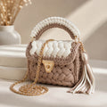 Woven handbag with braided handle and tassel on a neutral background
